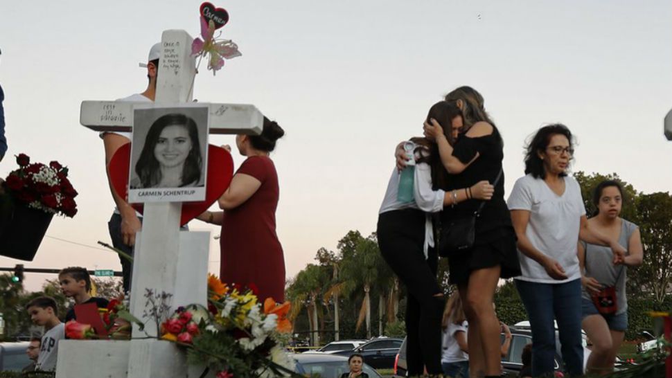 Magaly Newcomb, right comforts her daughter Haley Newcomb, 14, a student at Marjory Stoneman Douglas High School, at a makeshift memorial outside the school, in Parkland, Fla., Sunday, Feb. 18, 2018. Nikolas Cruz, a 19-year-old who had been expelled from the school, is being held without bail in the Broward County Jail, accused of 17 counts of first-degree murder. (AP Photo/Gerald Herbert)