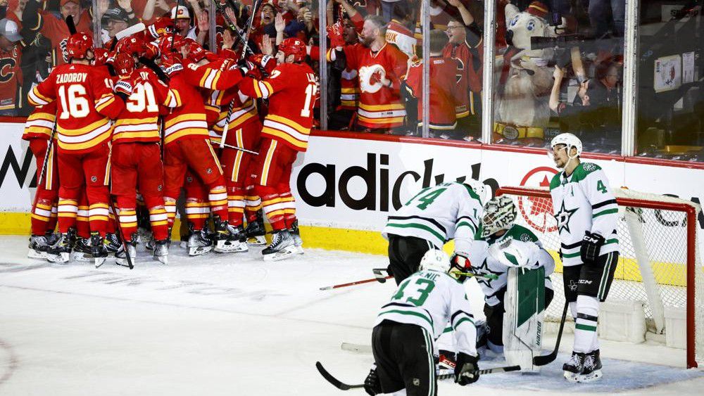 Dallas Stars goalie Jake Oettinger, second from right, is consoled by teammates as Calgary Flames celebrate following overtime NHL playoff hockey action in Calgary, Alberta, Sunday, May 15, 2022. (Jeff McIntosh/The Canadian Press via AP)