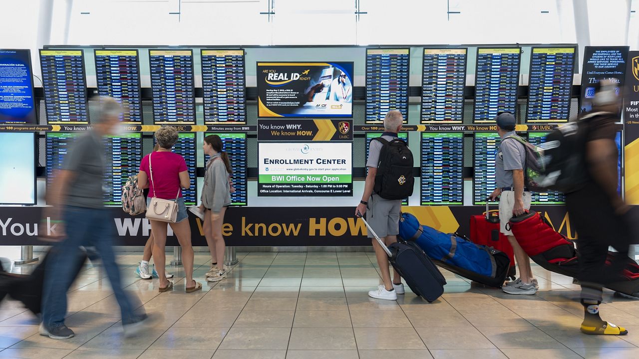 Travelers look at a flight information display system at Baltimore/Washington International Thurgood Marshall Airport in Baltimore, Friday, July 19, 2024. (AP Photo/Stephanie Scarbrough)