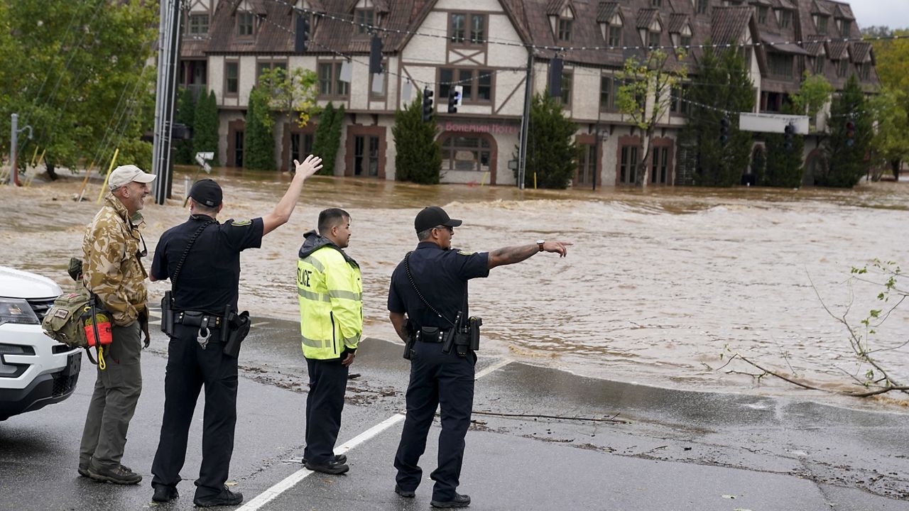 Emergency personnel watch as floodwaters rise, Friday, Sept. 27, 2024, in Asheville, N.C. (AP Photo/Erik Verduzco)