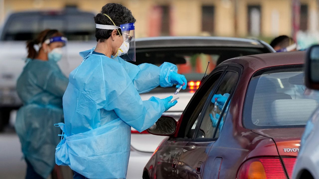 Health workers perform COVID-19 tests at a drive-up testing center. (AP/Rebecca Blackwell)