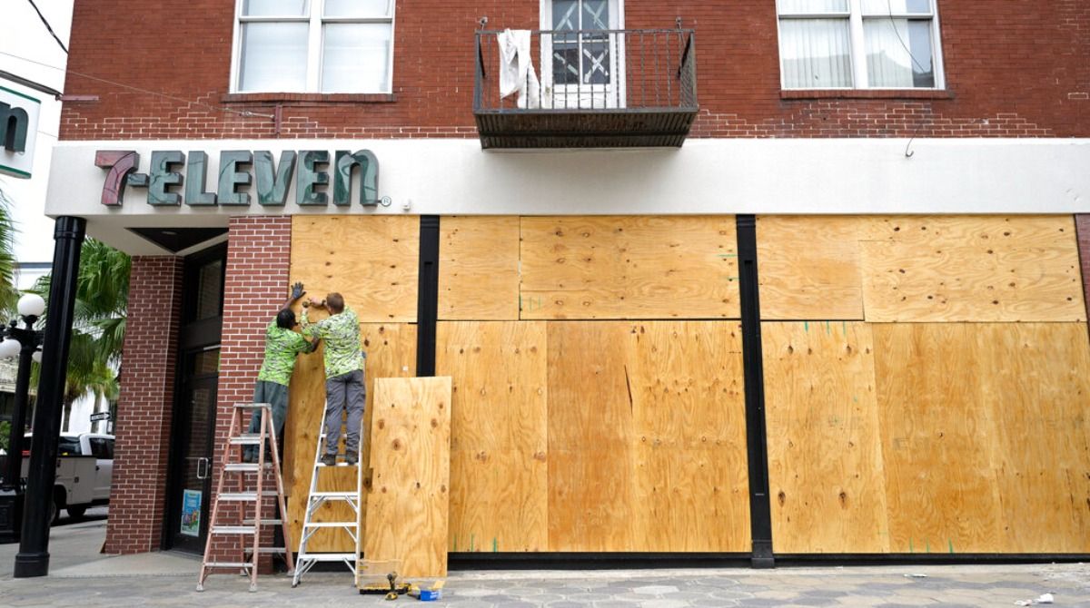Workers board up the windows of a 7-Eleven convenience store in the Ybor City district in preparation for Hurricane Ian approaches the western side of the state, Tuesday, Sept. 27, 2022, in Tampa, Fla. 