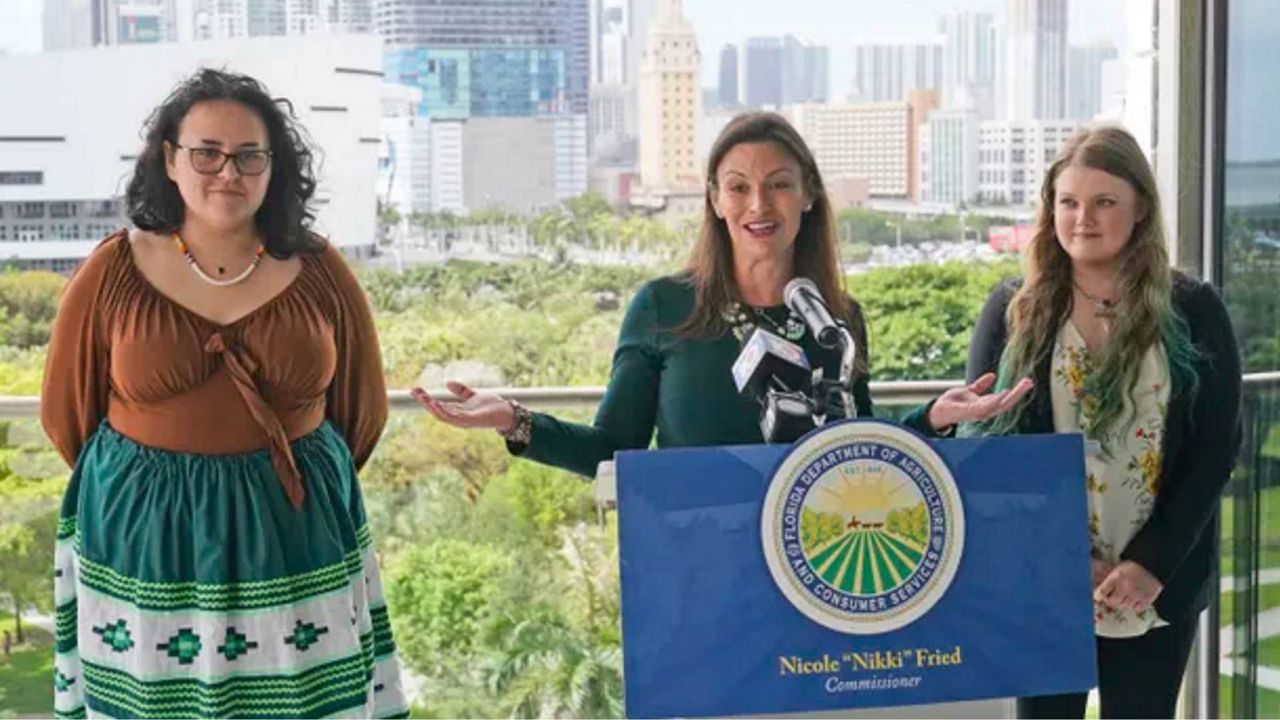 Florida Commissioner of Agriculture and Consumer Services Nikki Fried (center), speaks during a news conference along with youth climate leaders, Valholly Frank (left) and Delaney Reynolds (right) Thursday, April 21, 2022 at the Philip & Patricia Frost Museum of Science in Miami. Fried unveiled a proposed rule that requires utilities operating in the state generate 100% of their electricity from renewable sources of energy by 2050. (AP Photo/Wilfredo Lee)