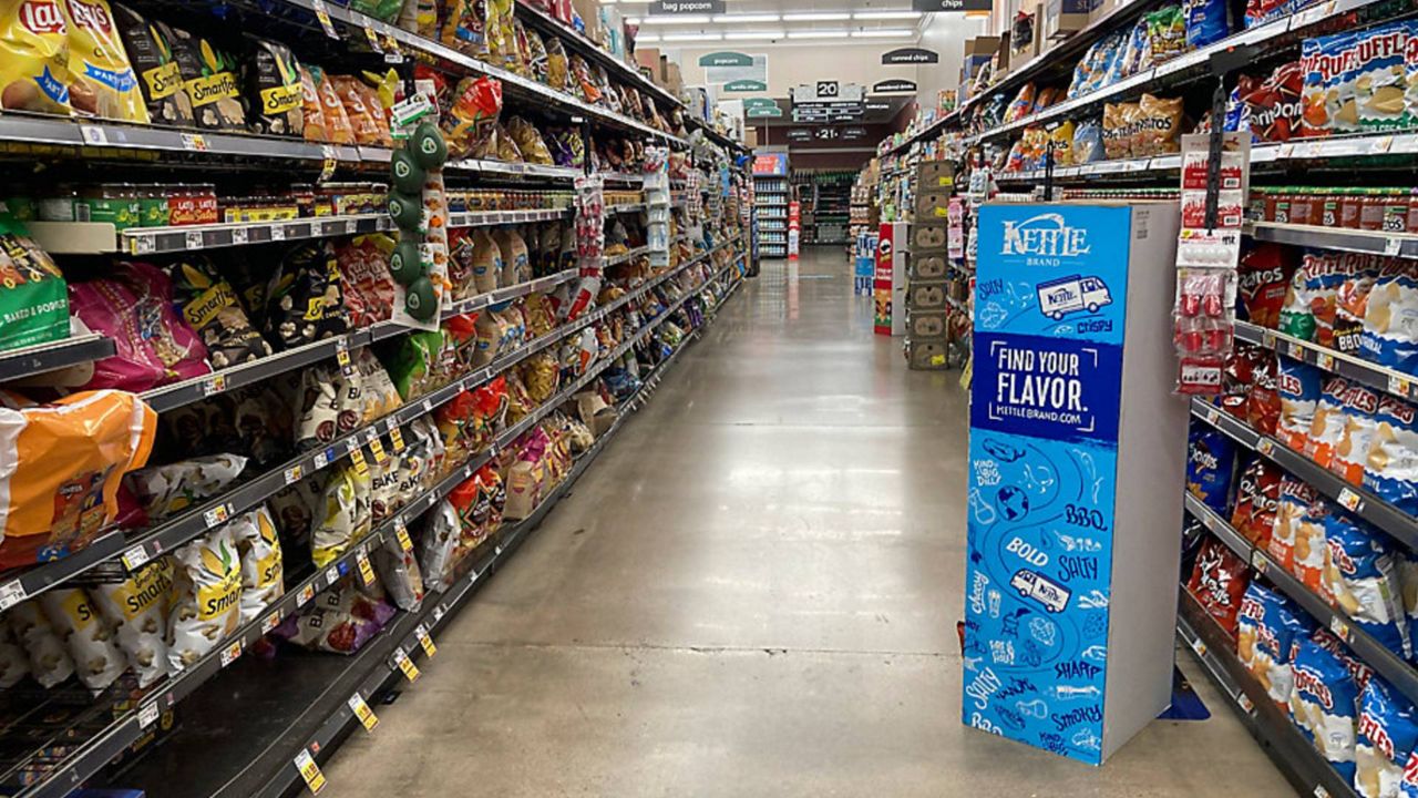 Displays of bags of snack foods frame an aisle without a customer in a King Soopers grocery store Friday, Jan. 21, 2022, in southeast Denver. (AP Photo/David Zalubowski)