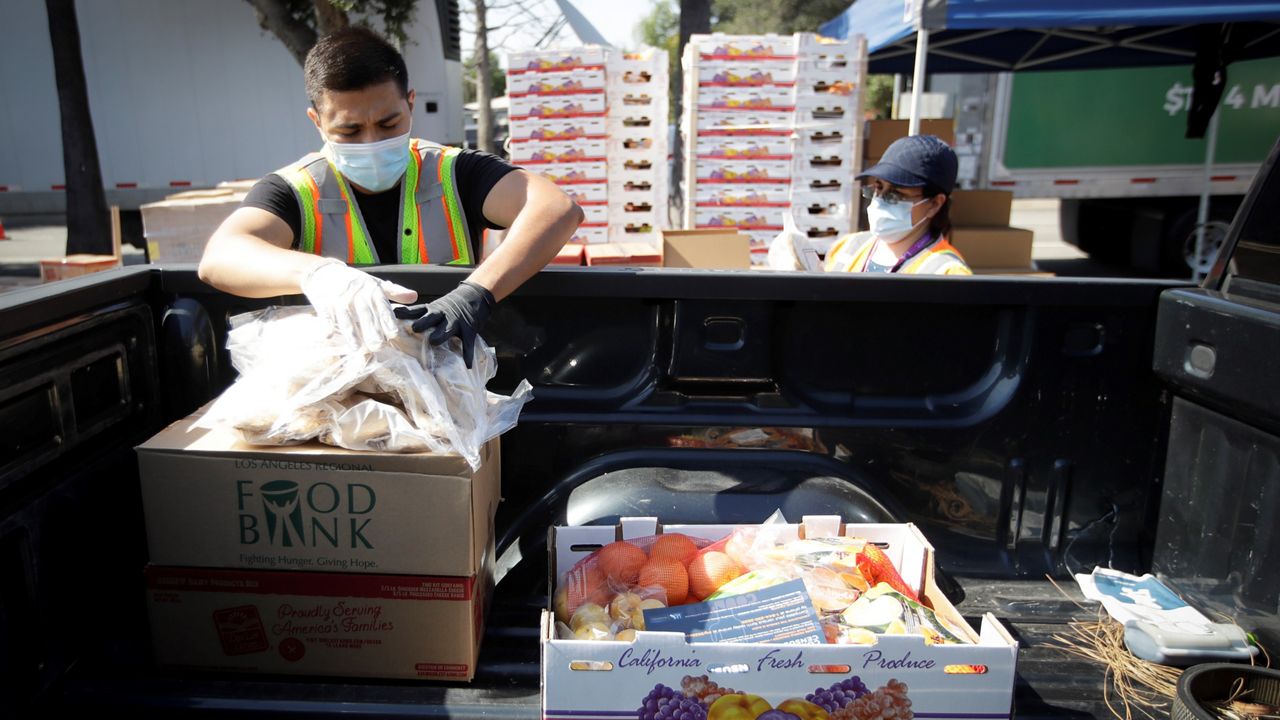 Volunteers load up a pick up truck at a food distribution center Wednesday, July 22, 2020, in the Mission Hills area of Los Angeles. (AP Photo/Marcio Jose Sanchez)