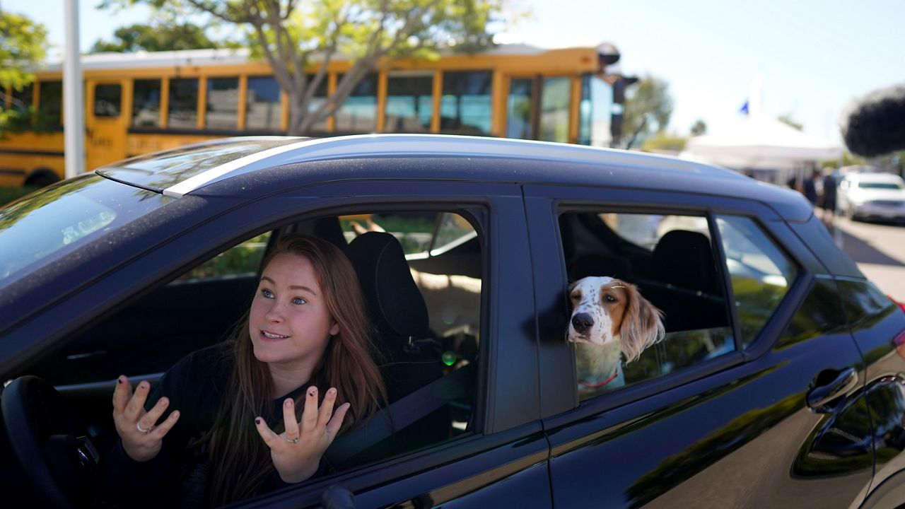 Brooklyn Pittman talks as she sits in her car with her dogs after receiving food from an Armed Services YMCA food distribution, Oct. 28, 2021, in San Diego. (AP Photo/Gregory Bull)