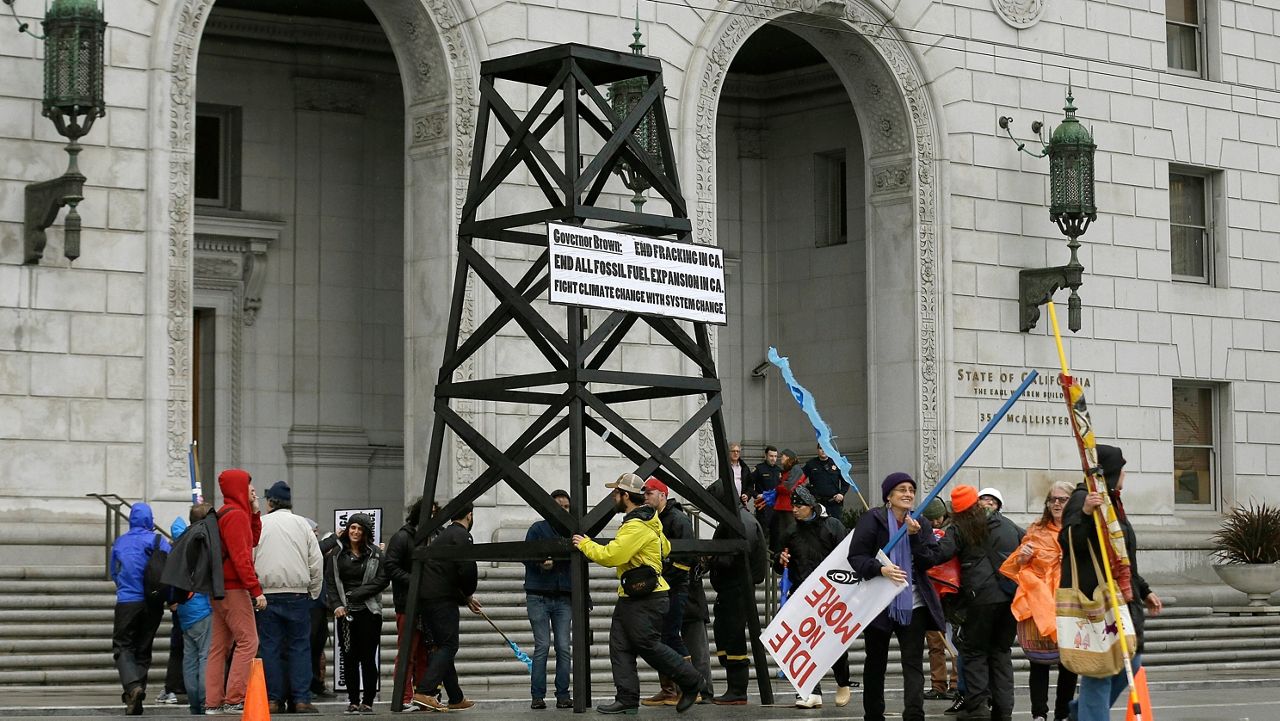 Protesters prepare to take down a makeshift oil derrick that was set up in front of the California State Office Building to protest fracking in San Francisco on Feb. 6, 2015. (AP Photo/Jeff Chiu, File)