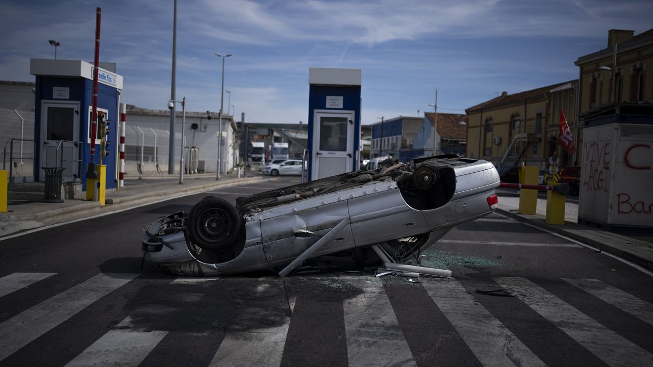 A destroyed car placed by dock workers blocks the Marseille port entrance in Marseille, France, on Friday. (AP Photo/Daniel Cole) 