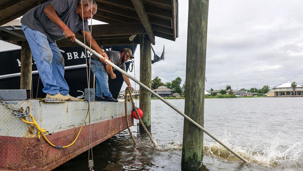 Norman Bouisse, 76, left, and Jeremy Adam, back left, one of the captains for the 100-foot trawler Master Brandon, work at tying extra lines around a piling in their attempt to batten down their boat in anticipation of Hurricane Francine along the Louisiana coast in Lafitte on Monday, Sept. 9, 2024. (Chris Granger/The Times-Picayune/The New Orleans Advocate via AP)