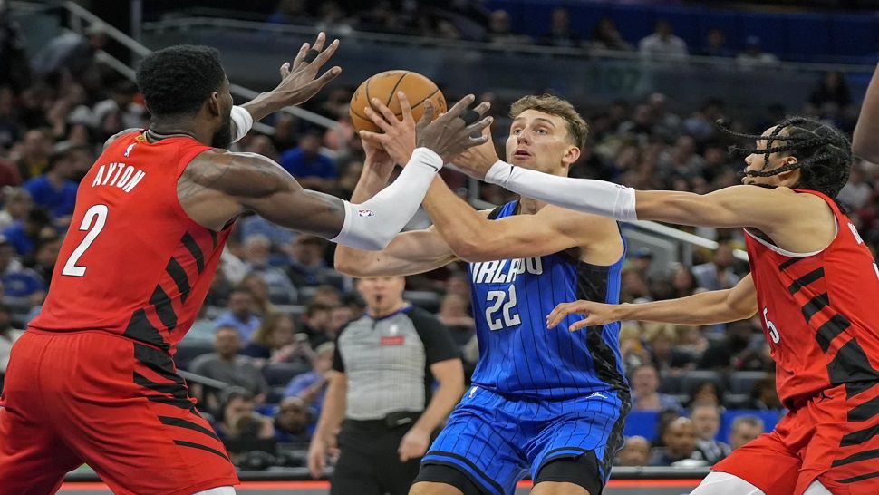 Orlando Magic forward Franz Wagner (22) looks for an open shot as he is caught between Portland Trail Blazers center Deandre Ayton (2) and guard Dalano Banton, right, during the second half of an NBA basketball game, Monday, April 1, 2024, in Orlando, Fla. (AP Photo/John Raoux)