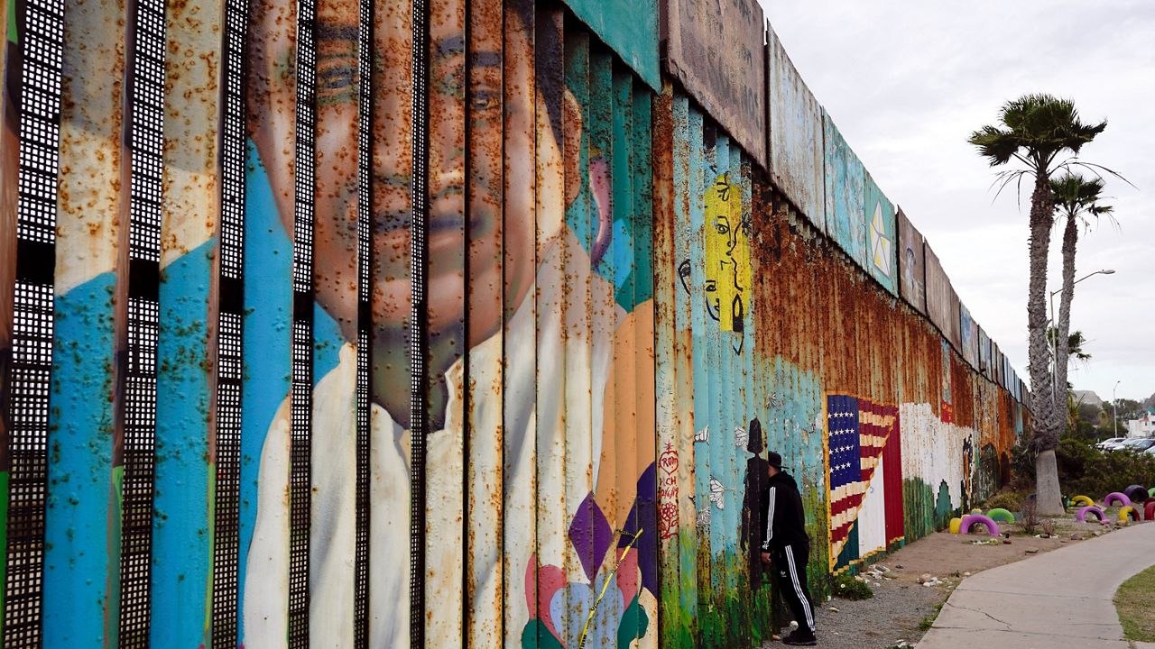 A man looks through the wall at Friendship Park, near where the border separating Tijuana, Mexico, and San Diego meets the Pacific Ocean on Jan. 19, 2021, in Tijuana, Mexico. (AP Photo/Gregory Bull, File)