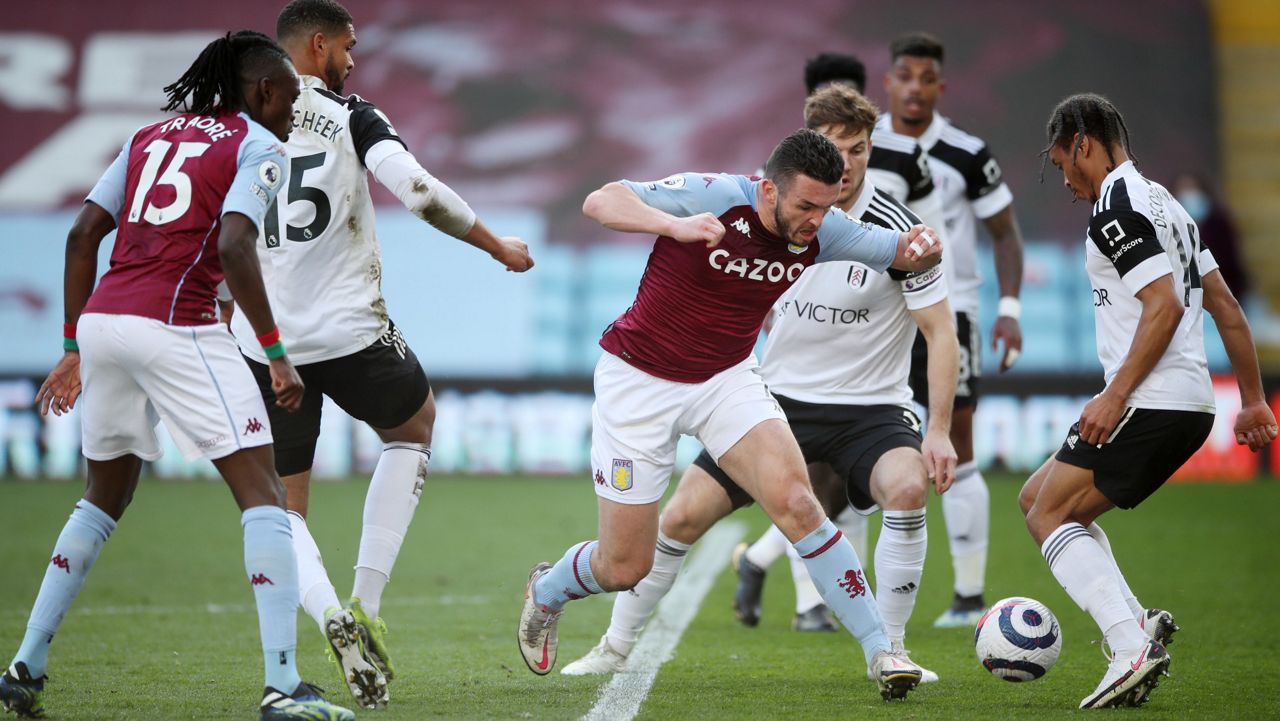 Aston Villa's John McGinn, centre, tries to get through the Fulham defence during an English Premier League soccer match between Aston Villa and Fulham at Villa Park in Birmingham, England, Sunday April 4, 2021.