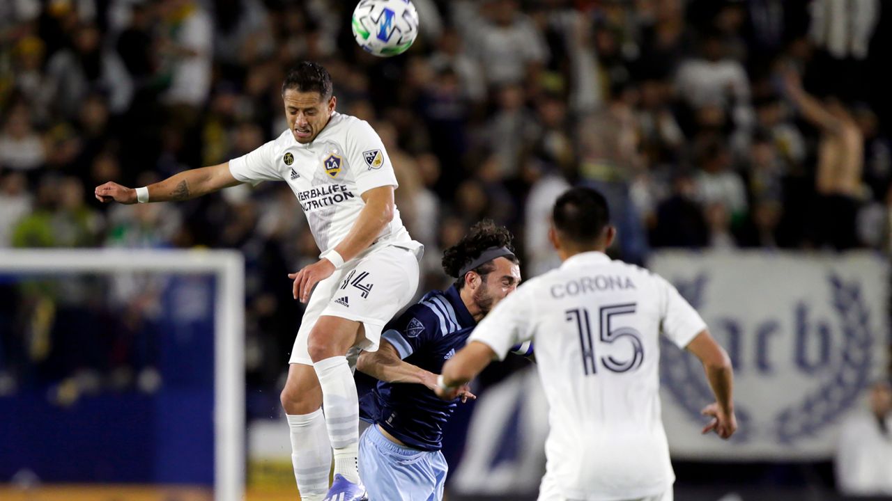 LA Galaxy forward Javier Hernandez, left, heads the ball away from Vancouver Whitecaps midfielder Russell Teibert, center, with midfielder Joe Corona, right, watching during the first half of an MLS soccer match in Carson, Calif., Saturday, March 7, 2020. (AP Photo/Alex Gallardo)