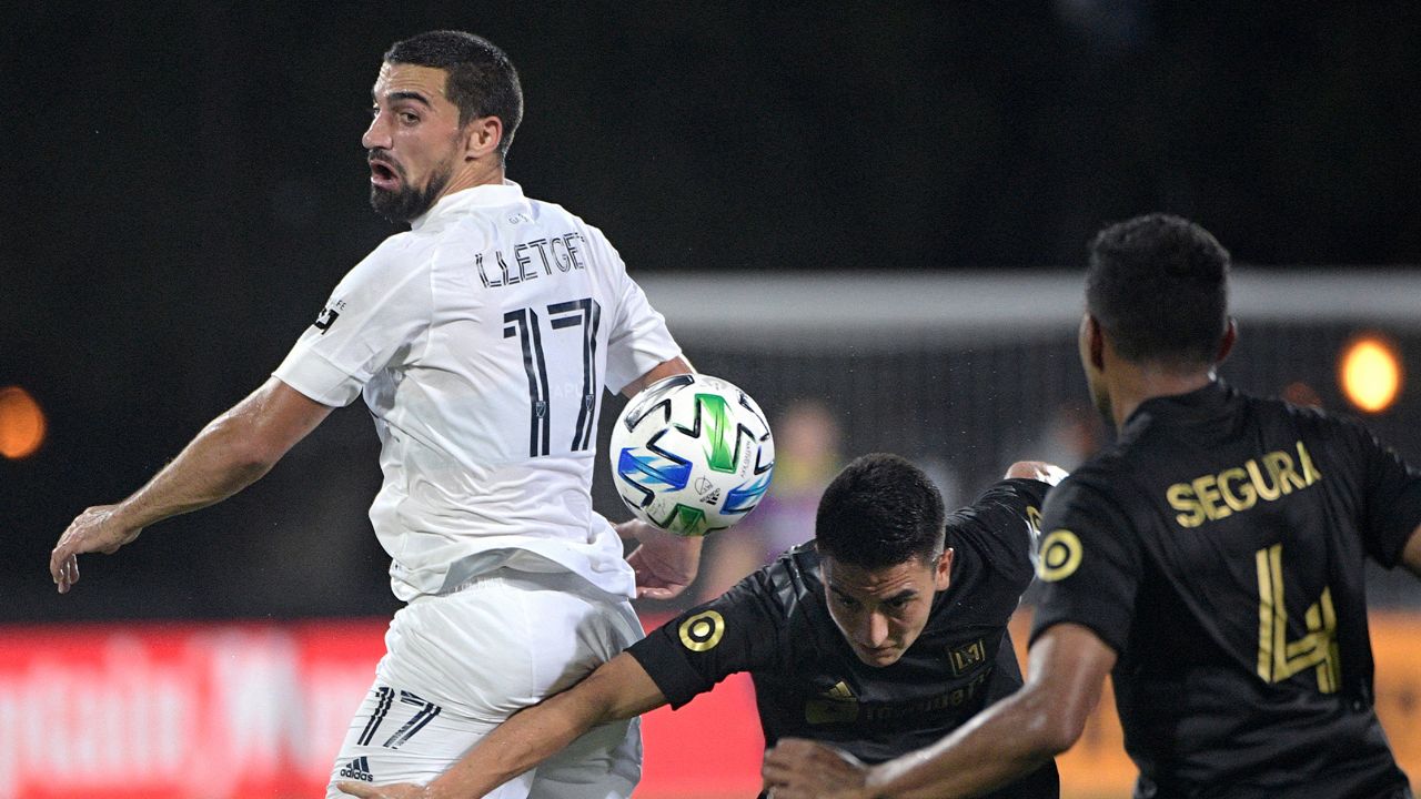 LA Galaxy midfielder Sebastian Lletget (17) competes for the ball with Los Angeles FC midfielder Eduard Atuesta (20) and defender Eddie Segura (4) during the first half of an MLS soccer match Saturday, July 18, 2020, in Kissimmee, Fla. (AP Photo/Phelan M. Ebenhack)