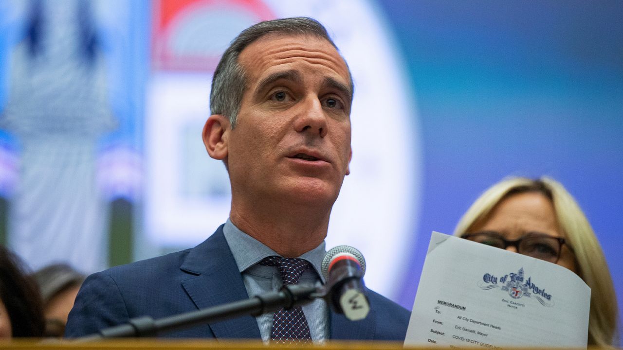 Los Angeles Mayor Eric Garcetti shows a Memorandum with COVID-19 city departments guidelines, as he takes questions at a news conference in Los Angeles, Thursday, March 12, 2020. (AP Photo/Damian Dovarganes)
