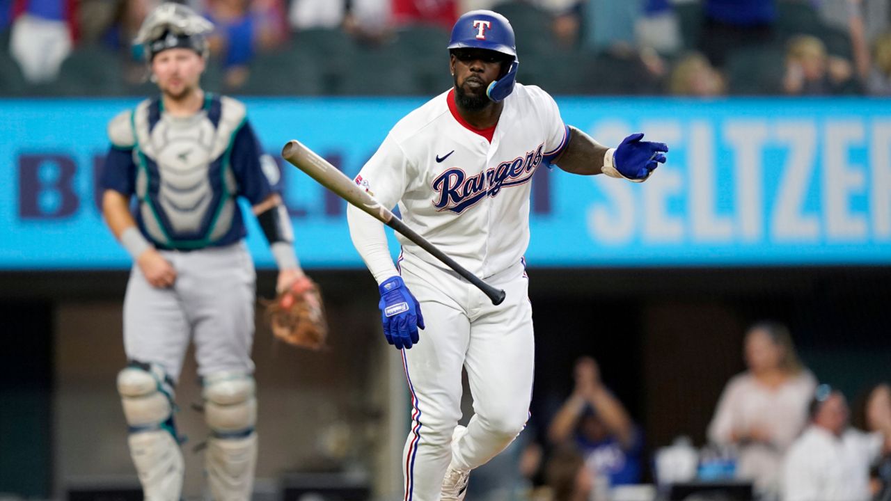 Texas Rangers' Adolis Garcia, right, tosses his bat in front of Seattle Mariners catcher Cal Raleigh, left, after hitting a three-run home run during the fourth inning of a baseball game in Arlington, Texas, Saturday, June 4, 2022. Rangers' Marcus Semien and Mitch Garver also scored on the play. (AP Photo/LM Otero)