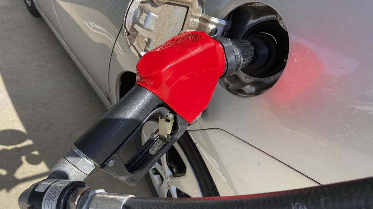 Red gas pump connected to a silver car.