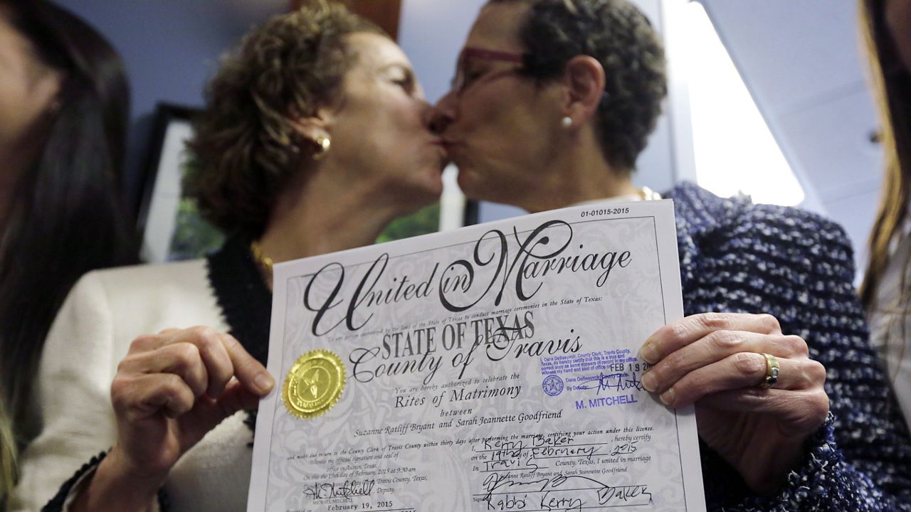 In this Feb. 19, 2015 file photo, Suzanne Bryant, left, and Sarah Goodfriend, right, exchange a kiss as they pose with their marriage license following a news conference in Austin, Texas. Despite Texas' longstanding ban on gay marriage at the time, the same-sex couple married immediately after being granted a marriage license under a one-time court order issued for medical reasons. (AP Photo/Eric Gay)