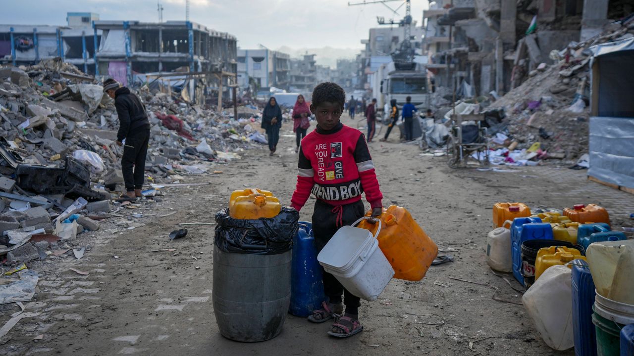 A young Palestinian kid carries jerricans along the destruction caused by the Israeli air and ground offensive in Jabaliya, Gaza Strip, Wednesday, Feb. 5, 2025. (AP Photo/Abdel Kareem Hana)