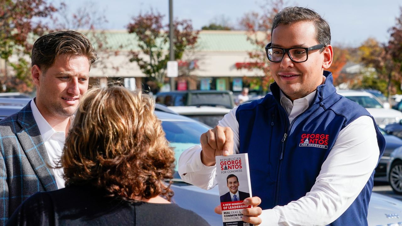 Republican candidate for New York's 3rd Congressional District George Santos, right, talks to a voter while campaigning outside a Stop and Shop store, Saturday, Nov. 5, 2022, in Glen Cove, N.Y. (AP Photo/Mary Altaffer)