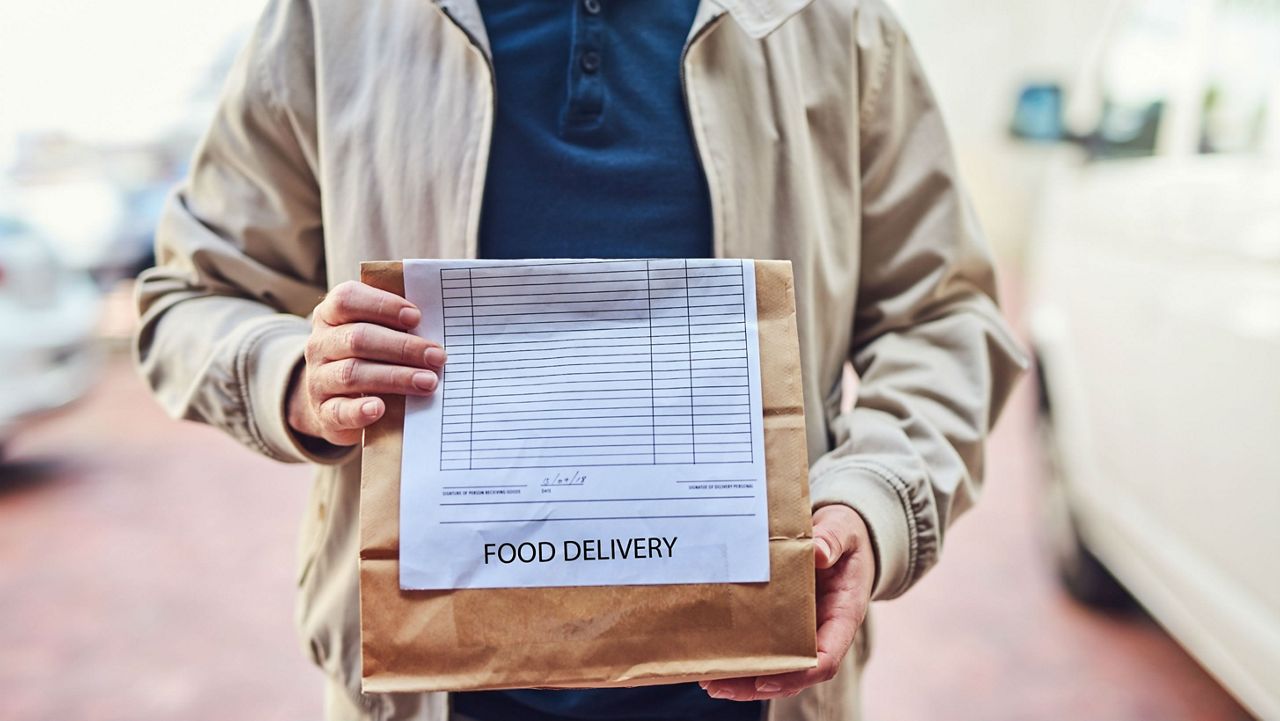 Stock image of a man holding a brown paper bag. (Getty Images)