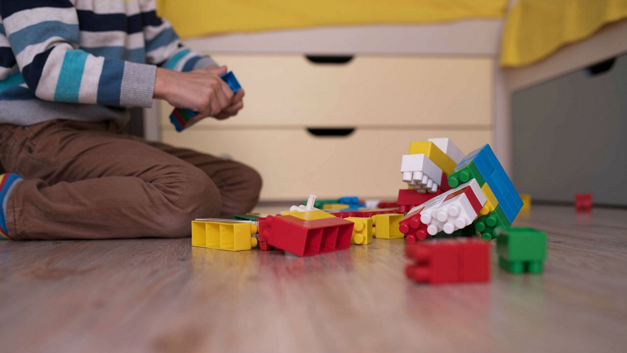 Stock image of a child sitting on the ground playing with blocks. (Getty Images)
