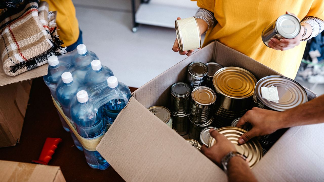 Stock image of volunteers putting canned food into boxes. (Getty Images)