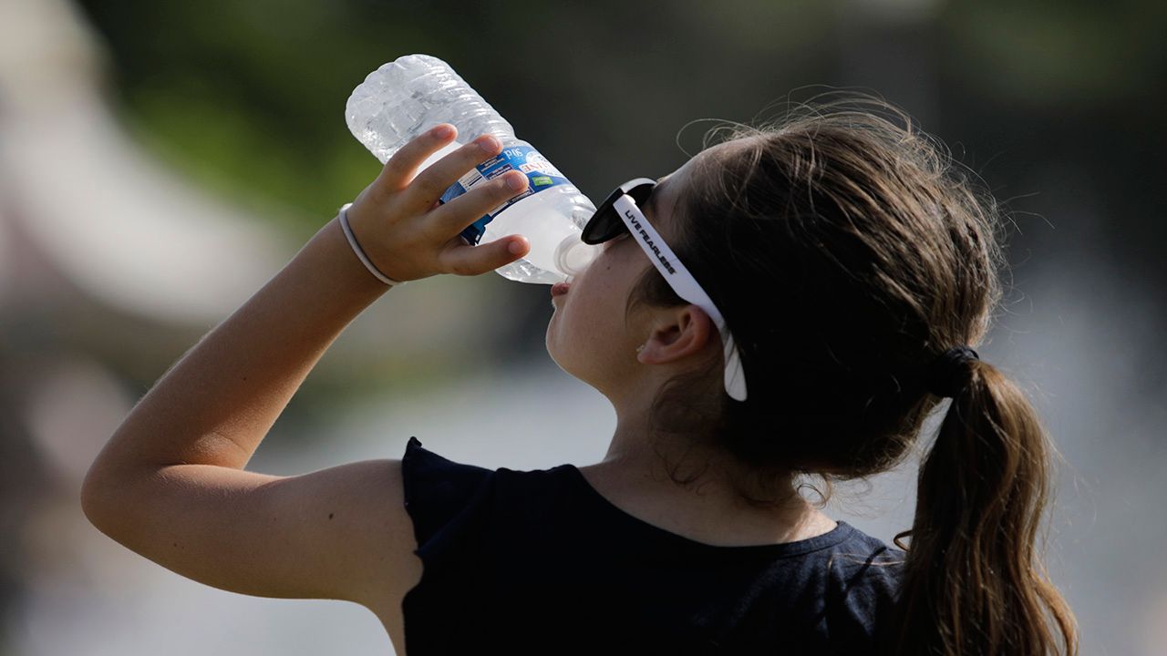 A girl drinks cool water in the Trocadero gardens near the Eiffel Tower in Paris