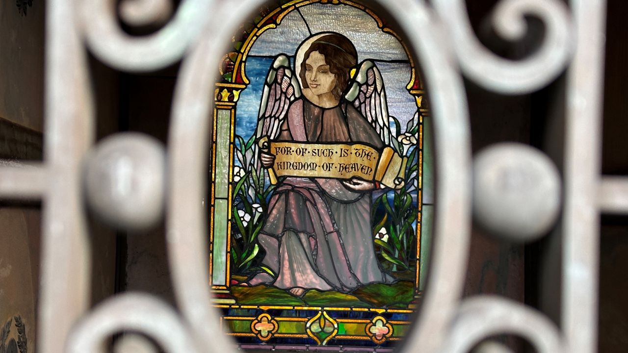 stained glass angel design in background and in focus, with wrought iron design in foreground out of focus