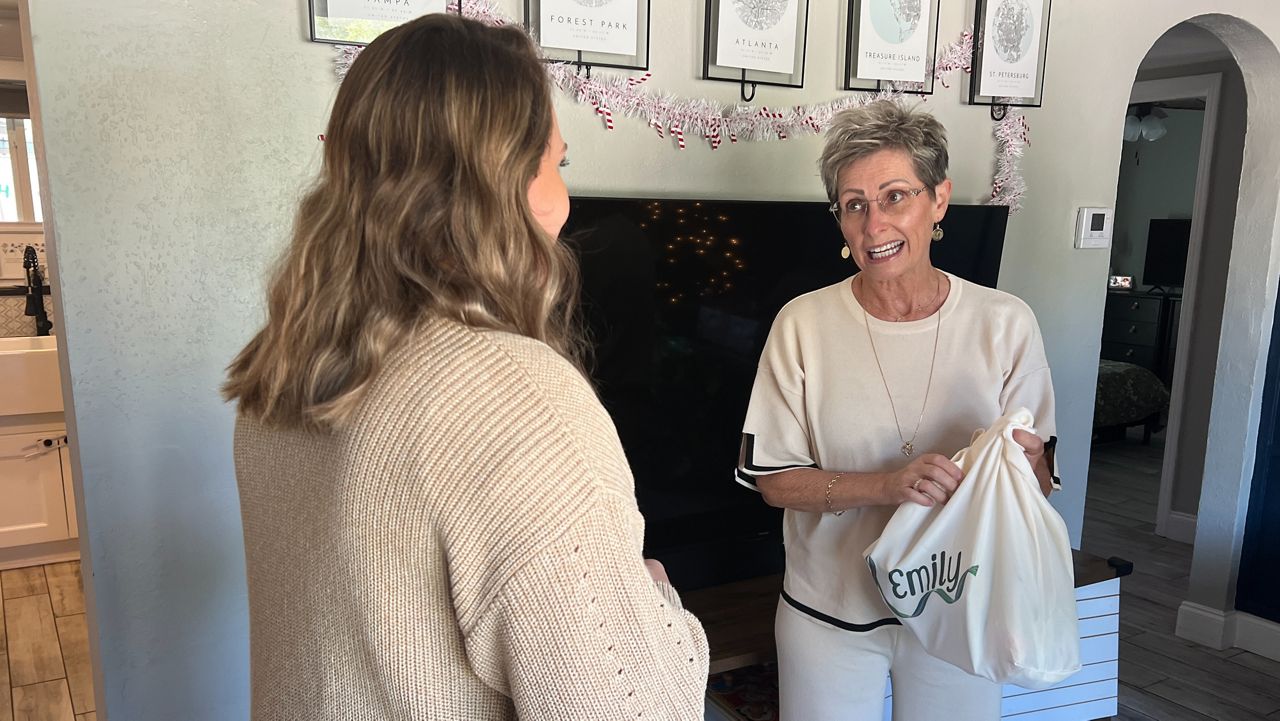 Denise Haynes (right) delivers presents to Emily Pearson (left), a mother with with metastatic breast cancer who has two children. (Spectrum News/Trevor Pettiford)