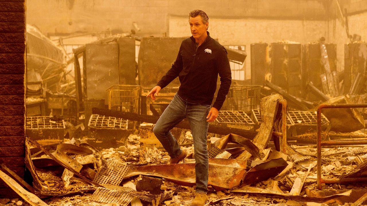 California Gov. Gavin Newsom walks over debris at the Greenville Post Office, which was destroyed by the Dixie Fire, on Saturday, Aug. 7, 2021, in Plumas County, Calif. (AP Photo/Noah Berger)