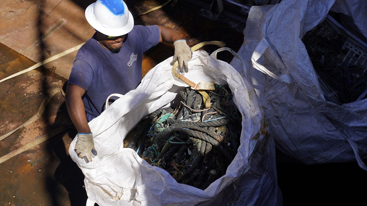 A crew member of the Ocean Voyages Institute sailing cargo ship Kwai prepares a bag of plastics and debris to be lifted from a hold during unloading in Sausalito, Calif., on July 27, 2022. The ship returned with the plastics from the ocean after 45 days in the area more commonly known as the "Great Pacific Garbage Patch." (AP Photo/Eric Risberg)