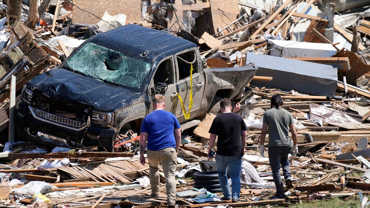 Local residents walk among the debris from tornado damaged homes, Wednesday, May 22, 2024, in Greenfield, Iowa. (AP Photo/Charlie Neibergall)