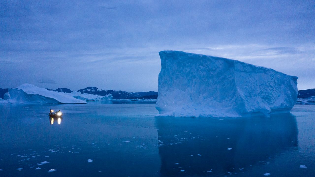 A boat navigates at night next to large icebergs in eastern Greenland on Aug. 15, 2019. (AP Photo/Felipe Dana, File)