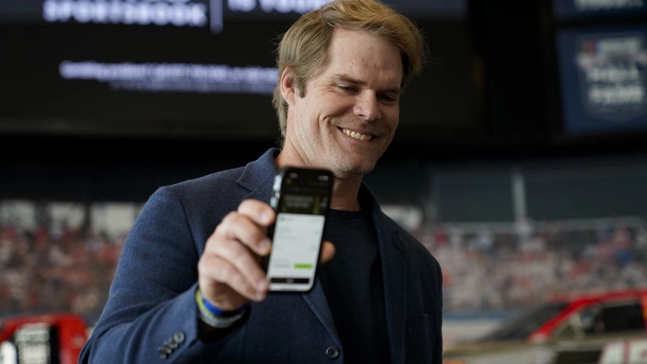 Fox Sports broadcaster Greg Olsen, who placed the first ceremonial bet in North Carolina, shows his receipt during a DraftKings event celebrating the launch of mobile and online sports wagering across the state at the NASCAR Hall of Fame, Monday, March 11, 2024, in Charlotte, N.C. (AP Photo/Erik Verduzco)