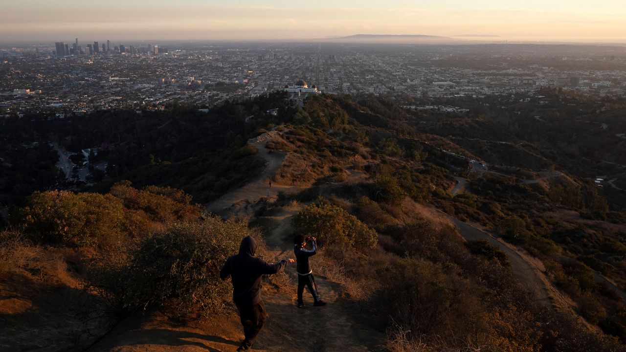 Two visitors walk along a trail at the Griffith Park overlooking the Los Angeles basin in Los Angeles, Monday, Nov. 14, 2022. (AP Photo/Jae C. Hong)
