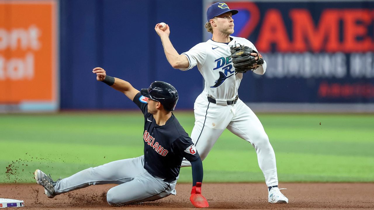 Tampa Bay Rays shortstop Taylor Walls, right, throws to first base after forcing out Cleveland Guardians' Steven Kwan, left, at second base during the first inning of a baseball game Friday, July 12, 2024, in St. Petersburg, Fla.