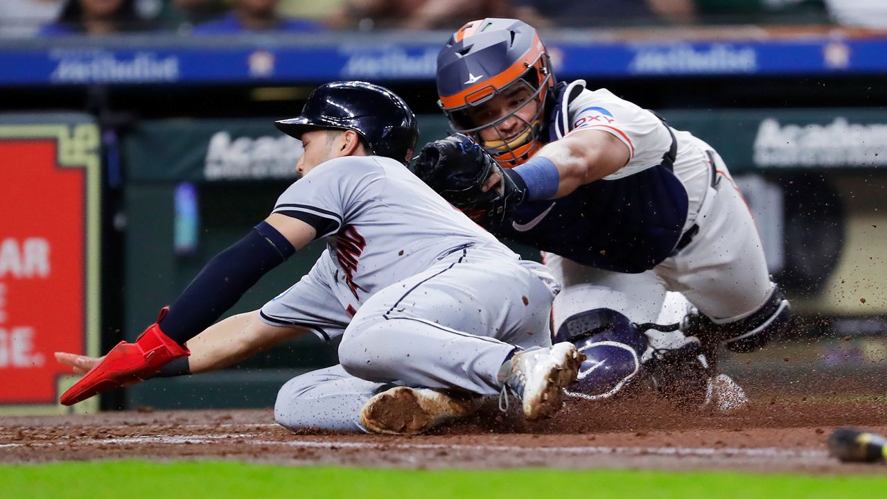 Cleveland Guardians' Steven Kwan, left, beat a tag-attempt by Houston Astros catcher Yainer Diaz, right, to score on the sacrifice fly by Jose Ramirez during the third inning of a baseball game Thursday, May 2, 2024, in Houston. (AP Photo/Michael Wyke)