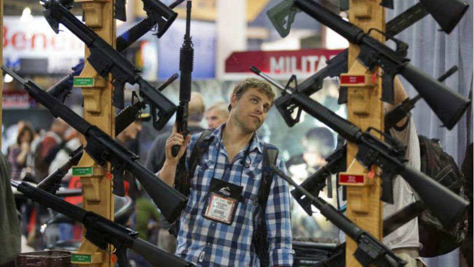 In this Jan. 27, 2013 file photo Michael Kiefer of DeFuniak Springs, Fla., checks out a display of rifles at the Rock River Arms booth during the 35th annual SHOT Show in Las Vegas. The largest gun industry trade show will be taking place in Las Vegas Jan. 23-26 just a few miles from where a gunman carried out the deadliest mass shooting in modern U.S. history. (AP Photo/Julie Jacobson)