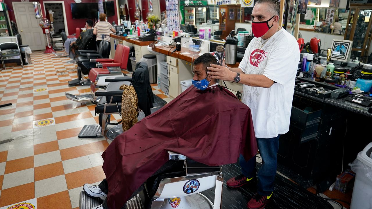 Edgar Gomez has his hair cut by George Garcia, owner of George's Barber Shop, Tuesday, July 14, 2020, in San Pedro, Calif. Gov. Gavin Newsom ordered that indoor businesses like salons, barber shops, restaurants, movie theaters, museums and others close due to the spread of COVID-19. (AP Photo/Ashley Landis)