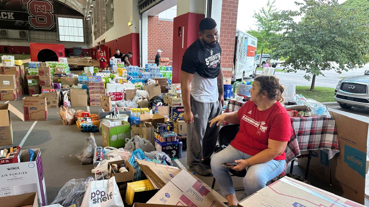 N.C. State defensive end Davin Vann and his mother, Joy Hall, work among the donations collected to help Hurricane Helene victims in western North Carolina, Wednesday, Oct. 2, 2024 in Raleigh, N.C. (AP Photo/Aaron Beard)