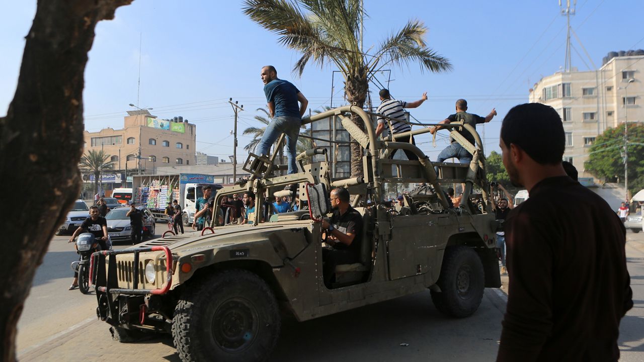 Palestinians ride on an Israeli military vehicle taken by an army base overrun by Hamas militants near the Gaza Strip fence, in Gaza City, Saturday, Oct. 7, 2023. (AP Photo/Abed Abu Reash)