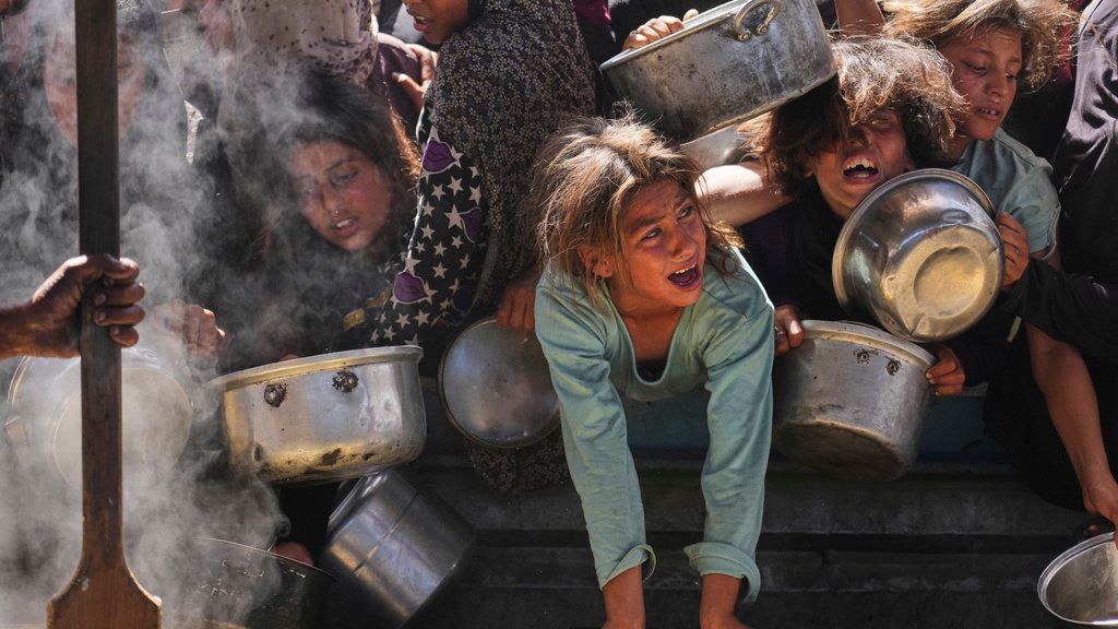 Niños palestinos luchan por conseguir alimentos donados en un comedor comunitario en Khan Younis, Franja de Gaza.