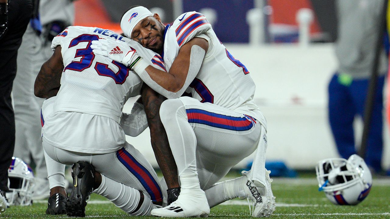 Bills players embrace one another while their teammate receives treatment on the field. (AP)