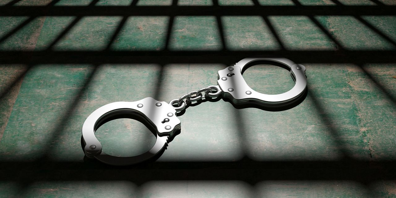 Handcuffs with shadow of jail bars. (Getty Images)