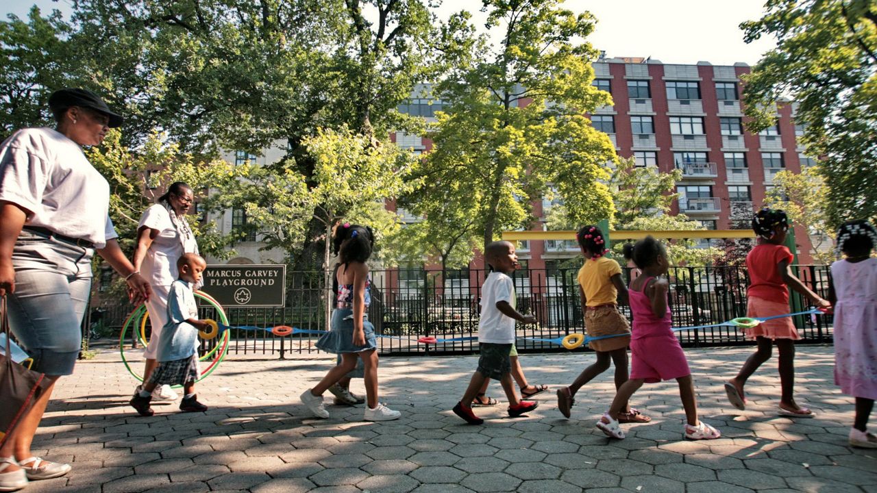 Children from a nearby day care are escorted in Marcus Garvey Park across the street.