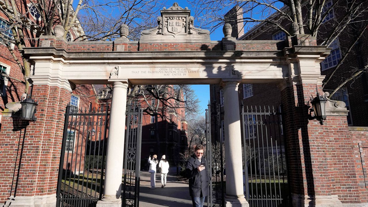 A passerby walks through a gate to the Harvard University campus, Tuesday, Jan. 2, 2024, in Cambridge, Mass. (AP Photo/Steven Senne, File)