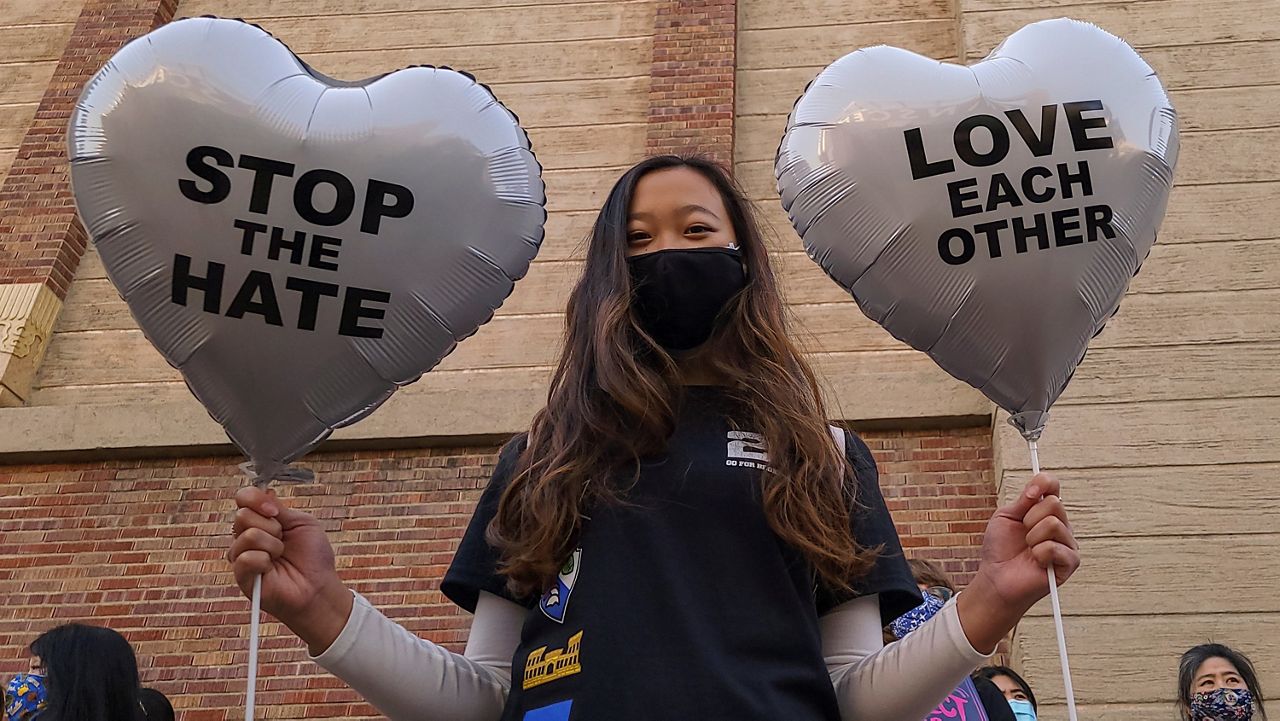 In this March 13, 2021, file photo, Chinese-Japanese American student Kara Chu, 18, holds a pair of heart balloons decorated by herself for the rally "Love Our Communities: Build Collective Power" to raise awareness of anti-Asian violence outside the Japanese American National Museum in Little Tokyo in Los Angeles. An annual report, released Wednesday, June 30, 2021, shows California hate crime reached its highest reported level in more than a decade last year. There was a doubling of crimes against those of Asian descent and a nearly 90% jump in those targeting Blacks (AP Photo/Damian Dovarganes, File)