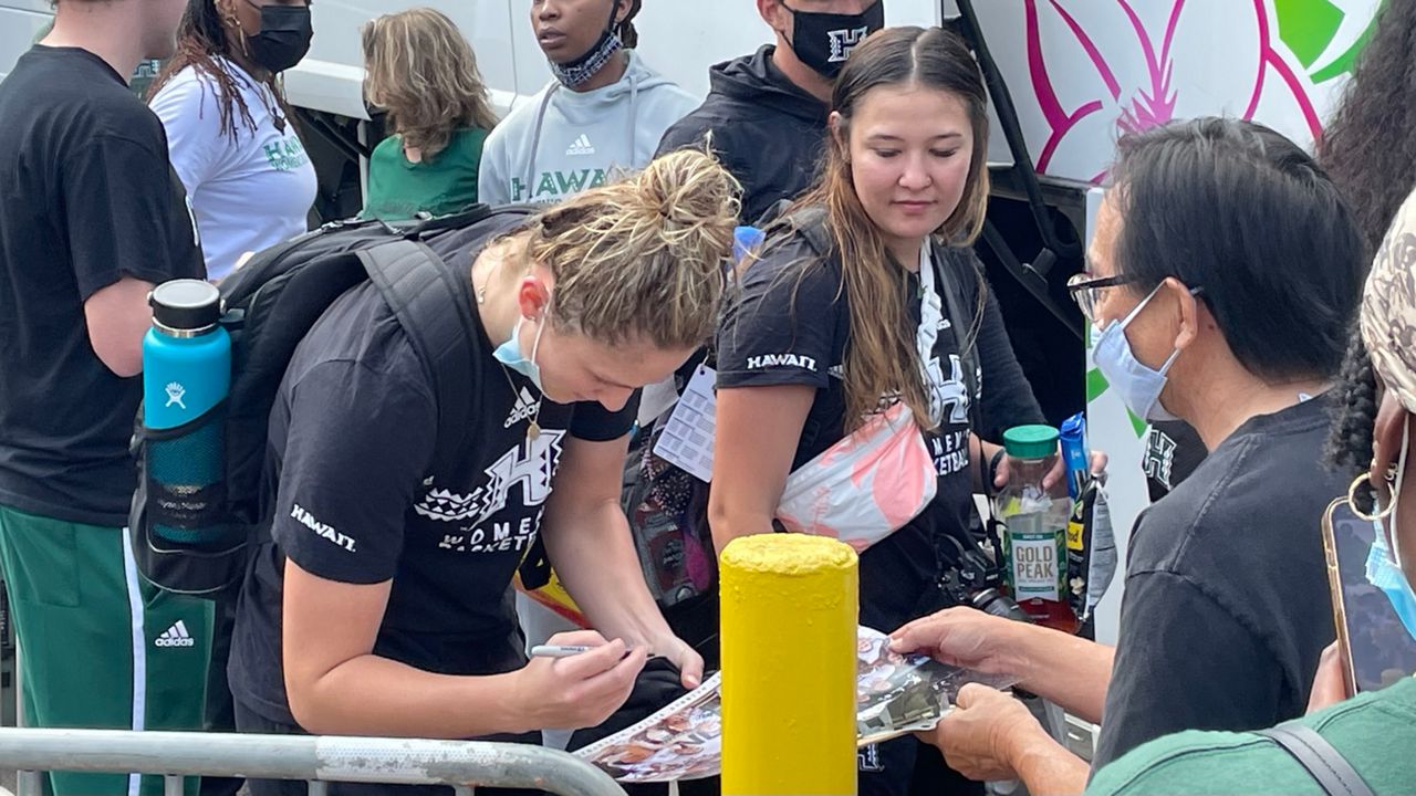 Hawaii women's basketball star Amy Atwell signed an autograph for a fan as teammate Kelsie Imai looked on before boarding the team bus to the airport on Tuesday. 
