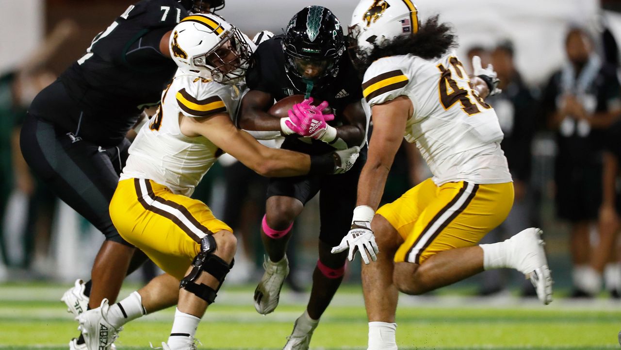 Wyoming defensive end Braden Siders (86) and linebacker Shae Suiaunoa (43) pulled down Hawaii running back Tylan Hines in the first half Saturday. 